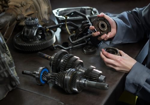 Close-up of female mechanic holding spare parts of car at repair garage