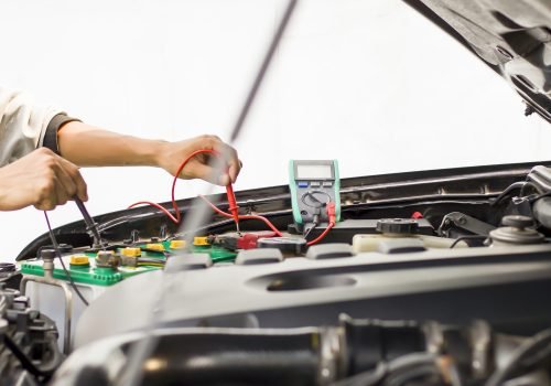 A technician is checking the car battery for availability.;